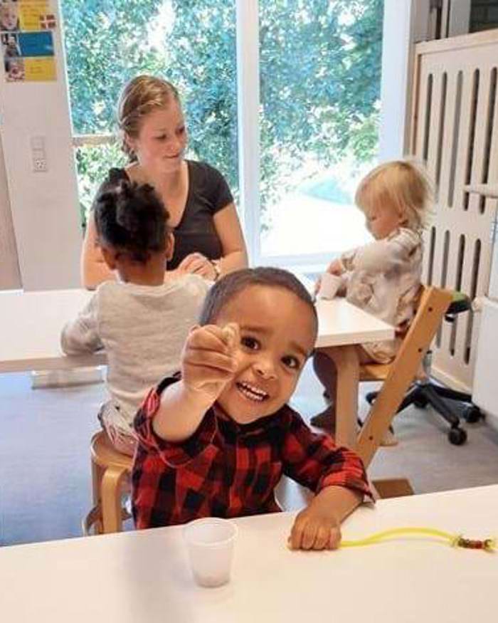 Børn og voksen laver perlekæder - de små fingre øver sig i finmotorik.