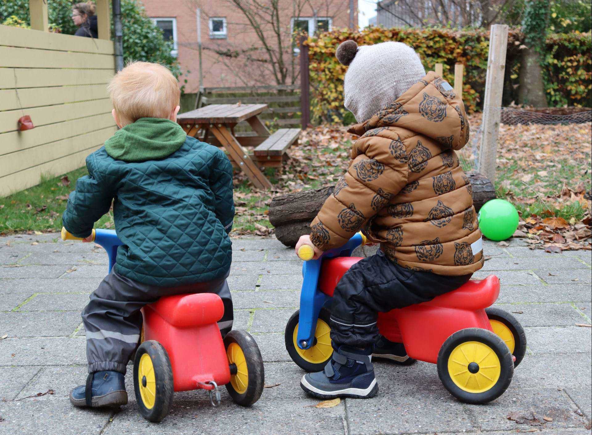 Børn kører på scooter på legepladsen