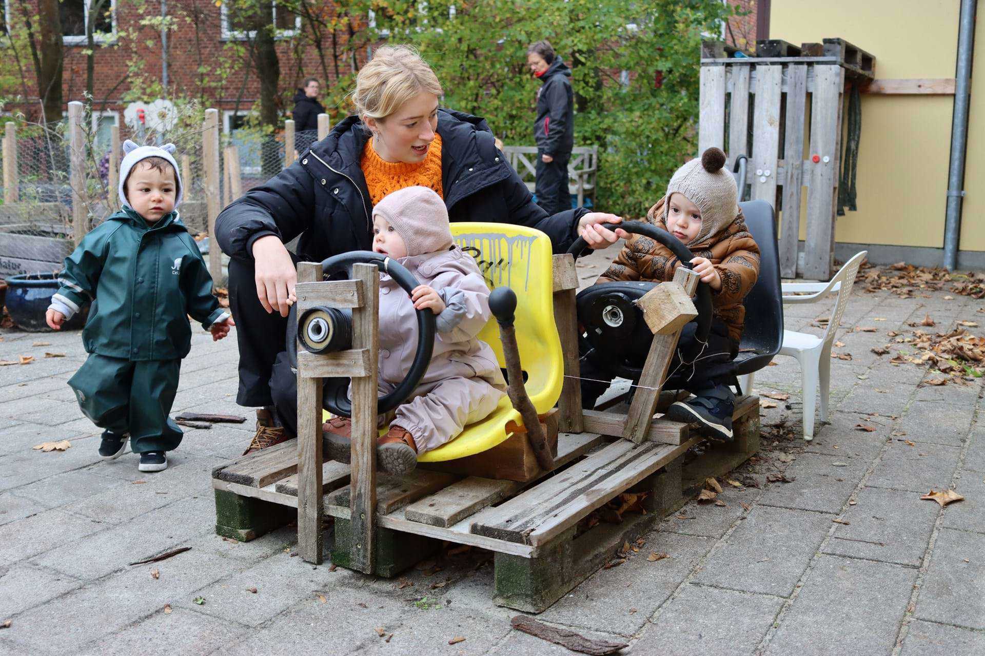 Børn og voksen leger bil - gad vide, hvor de er på vej hen?