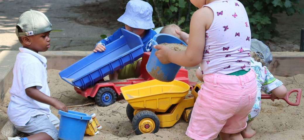 Vuggestuebørn leger i sandkassen - det er sjovt, for sand kan bruges til mange lege