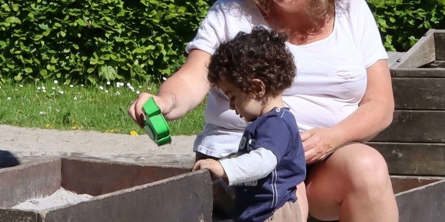 Børnene oplever både små og store fællesskaber. Her er et barn og en voksen helt fordybet i at lege med sand.