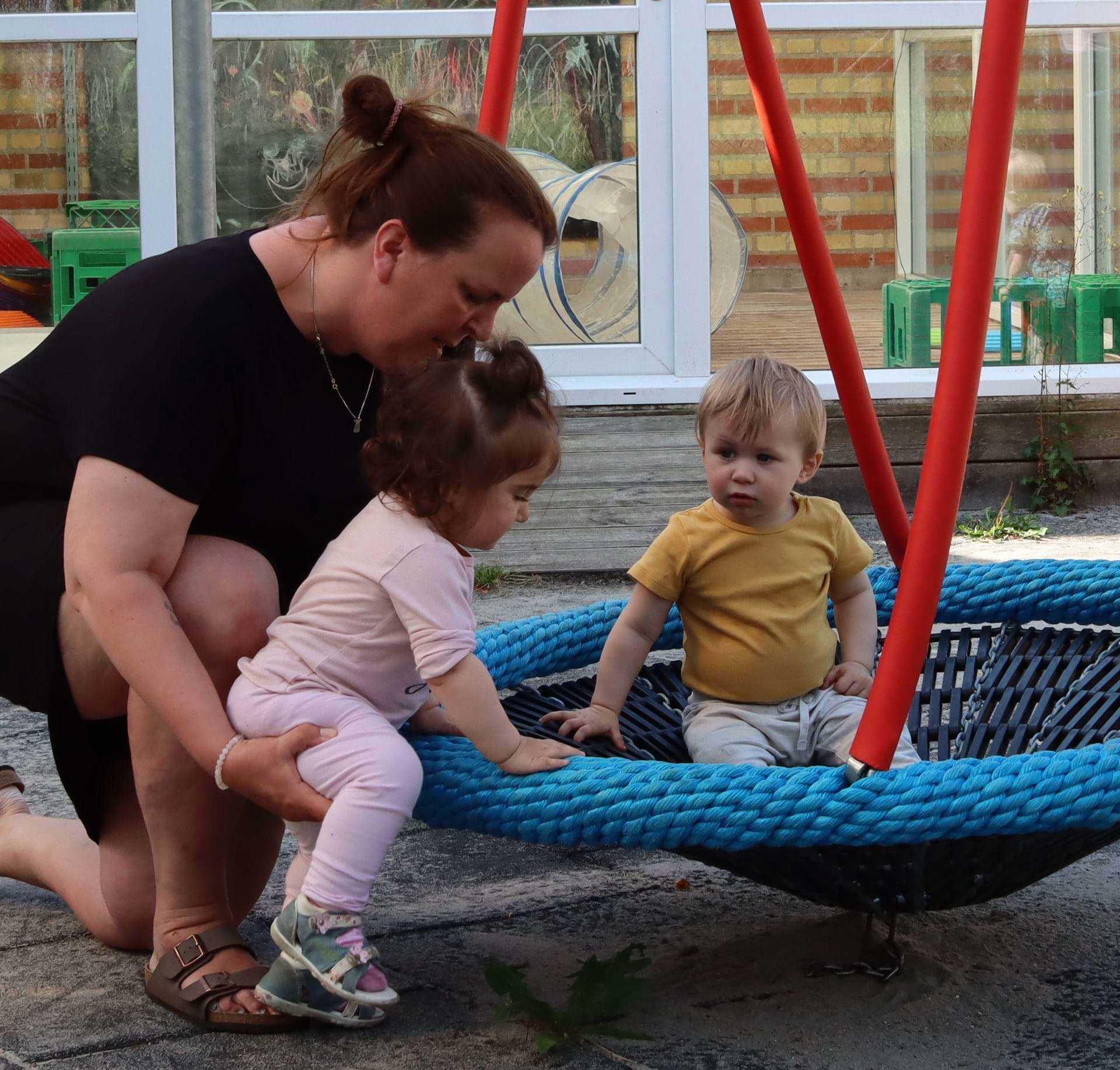 En hjælpende hånd - vi voksne hjælper børnene med at lære og blive så dygtige, som de kan. Her handler det om at komme op i gyngen.