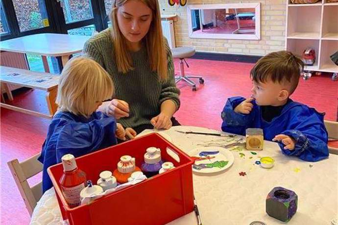 To børn har fundet mange flotte farver frem og er i gang med at lave en gave til deres forældre