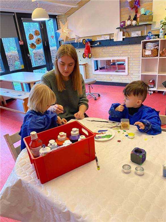 To børn har fundet mange flotte farver frem og er i gang med at lave en gave til deres forældre