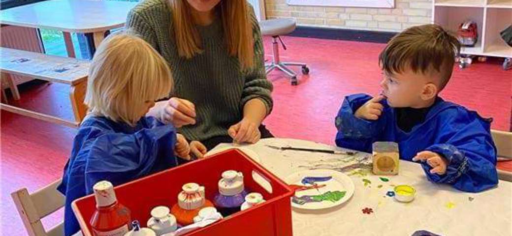 To børn har fundet mange flotte farver frem og er i gang med at lave en gave til deres forældre