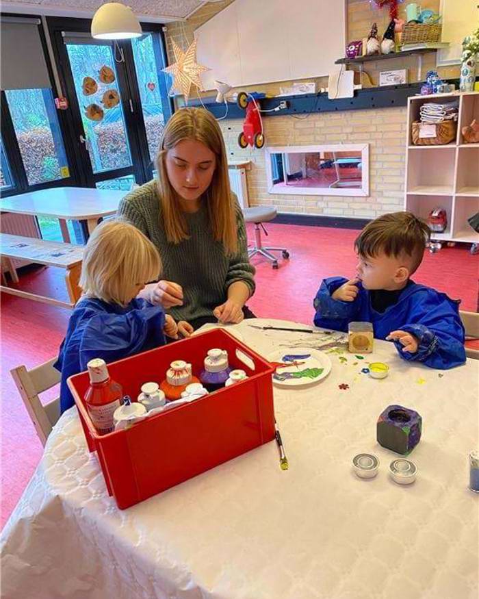 To børn har fundet mange flotte farver frem og er i gang med at lave en gave til deres forældre